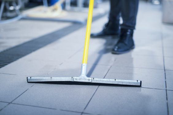 Close up of floor wiper mop cleaning industrial plant.